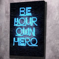 Dark canvas wall art with neon-blue text: “BE YOUR OWN HERO”