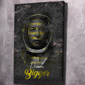 Wall art with glowing face outline and yellow “Dream Bigger” script on dark background