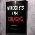 Black motivational wall art canvas with white and red text: WITH EVERY STEP I AM CHANGING.
