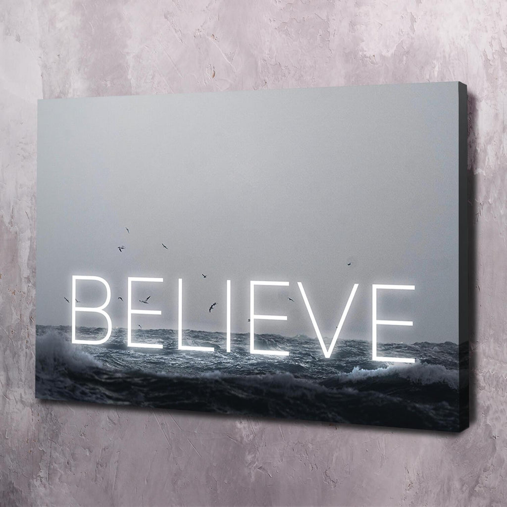 Motivational wall art canvas with glowing 'BELIEVE' over ocean waves, black frame