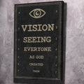 Black canvas wall art with eye icon and gold text: VISION, SEEING, EVERYONE, AS GOD