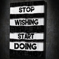 Motivational wall art reading STOP WISHING START DOING, white text on black stripes